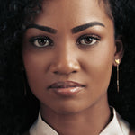 Front image of model wearing a gold cat head shaped drop earrings.