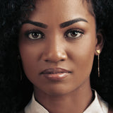 Front image of model wearing a gold cat head shaped drop earrings.