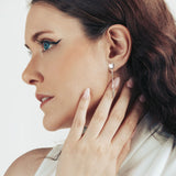 Model wearing a silver drop earring shaped as cat head with chain and spike at the end.