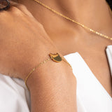 Model wearing a gold bracelet with cat head pendant.