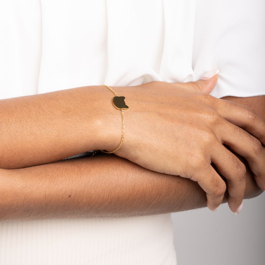 Model wearing a simple gold cat head bracelet on her arm.
