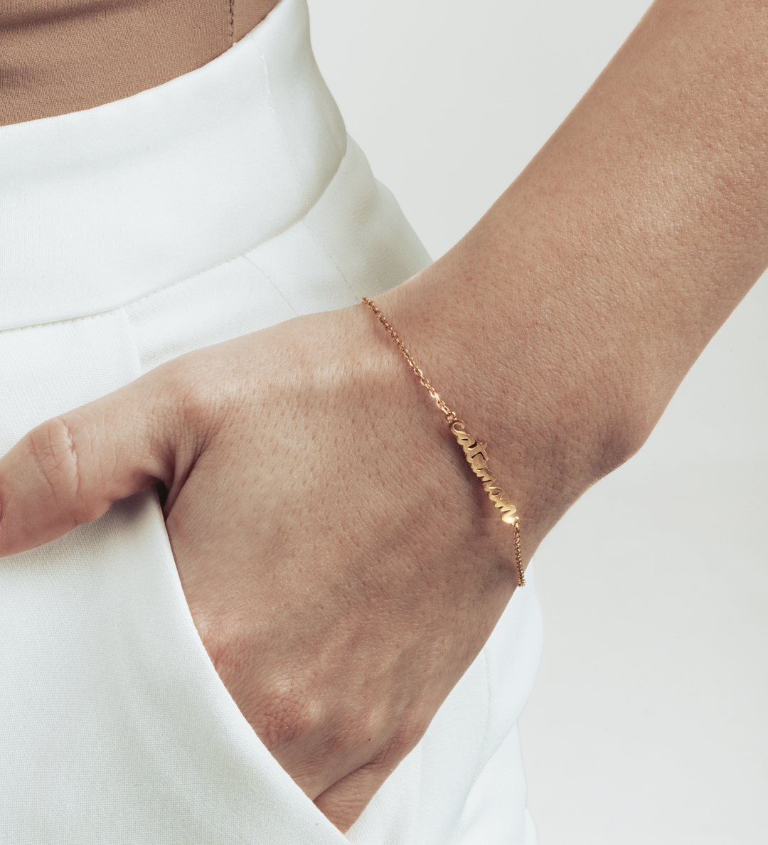 A hand in the pocket, visible gold cat mom letters bracelet.
