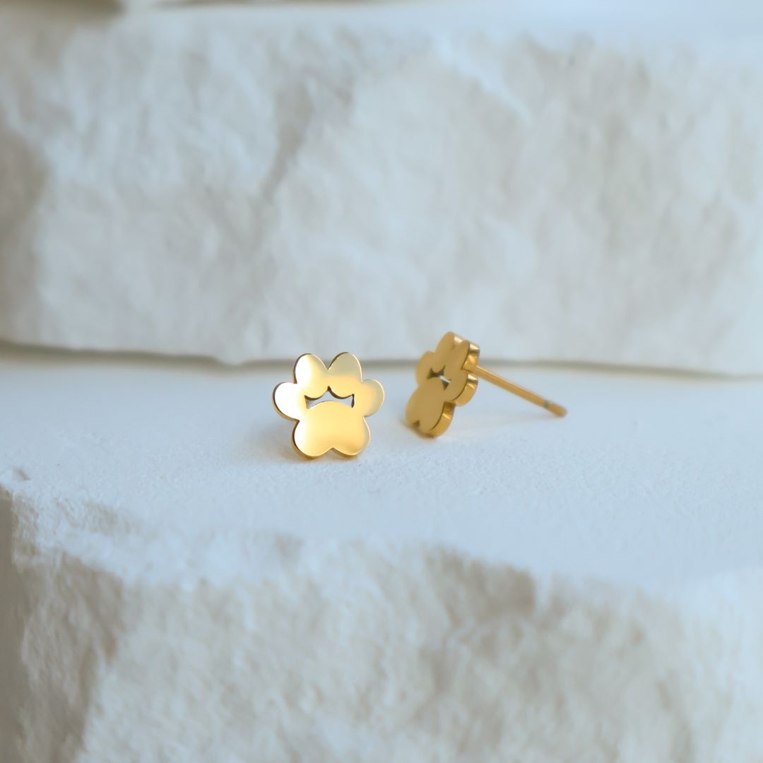 Lifestyle image of gold stud earrings in the shape of cat paws.