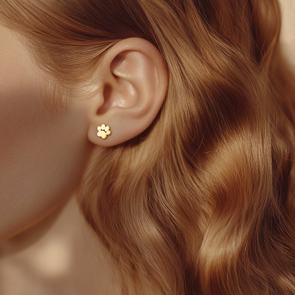 Close-up image of model wearing a gold paw shaped stud earring.