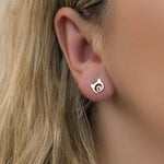 Close-up image on model of silver stud earring in the shape of cat head with little heart in the middle.