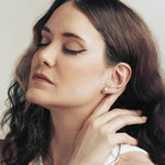 Model wearing silver stud earrings shaped as cat head with zirconia in the middle.