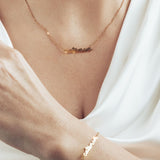 Model wearing a shiny gold cat mom necklace and matching bracelet.