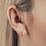 Model wearing a gold cat shaped stud earring with zirconia stone in the middle.