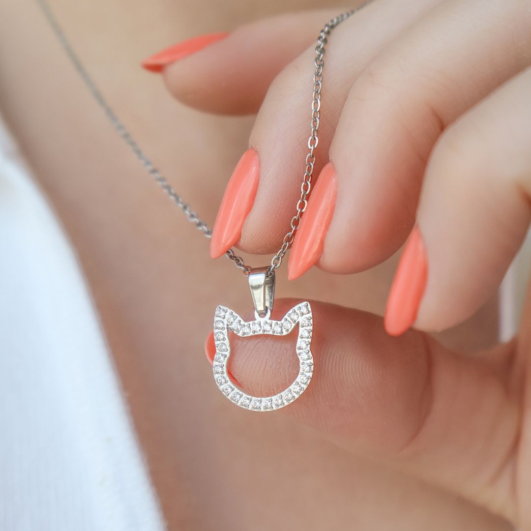 A close up image of silver necklace with the cat shaped pendant and zirconia stones.