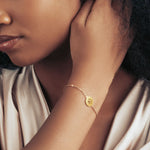 Model wearing a gold bracelet with paw print pendant.