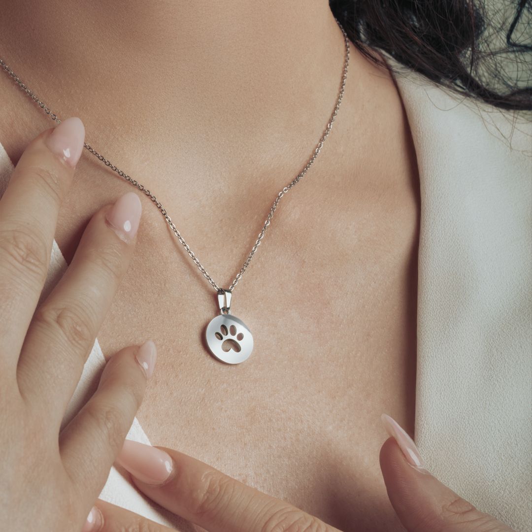 Close-up of the silver paw print necklace on a model’s neckline.