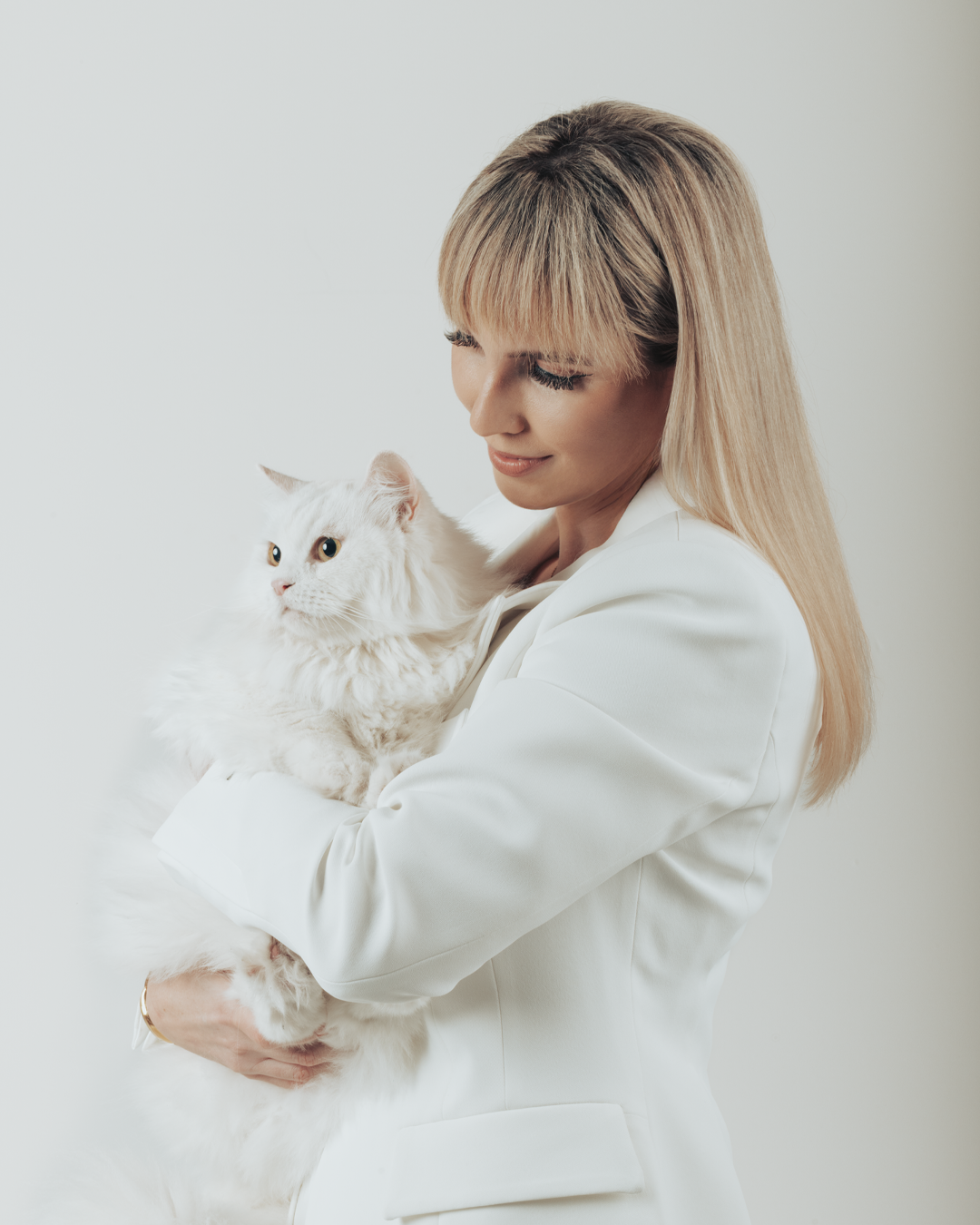 Anamarija Matijevic, a founder of Pretty4Paws is holding a fluffy white cat.