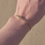 Video showing a model wearing cat mom gold bracelet wth the beach sand background.