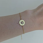 Video showing a gold-plated bracelet feturing simple round design with cat paw in the middle.