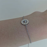 Video showing a stainless steel bracelet with round pendant and paw print in the middle.