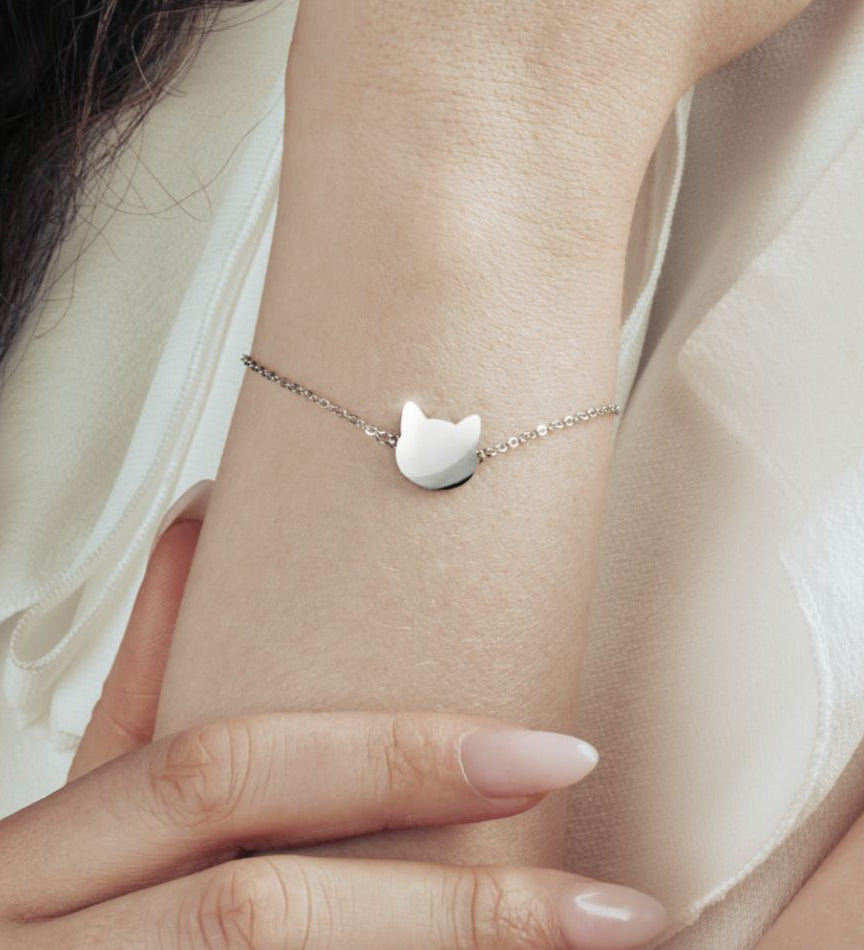 Model wearing a silver bracelet with simple and elegant cat head pendant. 