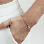 A hand in the pocket, visible gold cat mom letters bracelet. 