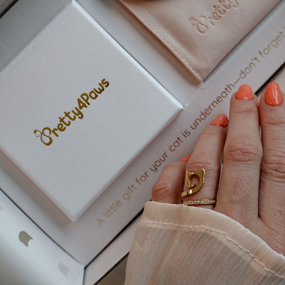 A close up lifestyle image of model's hand wearing an elegant gold cat ring with zirconia. 