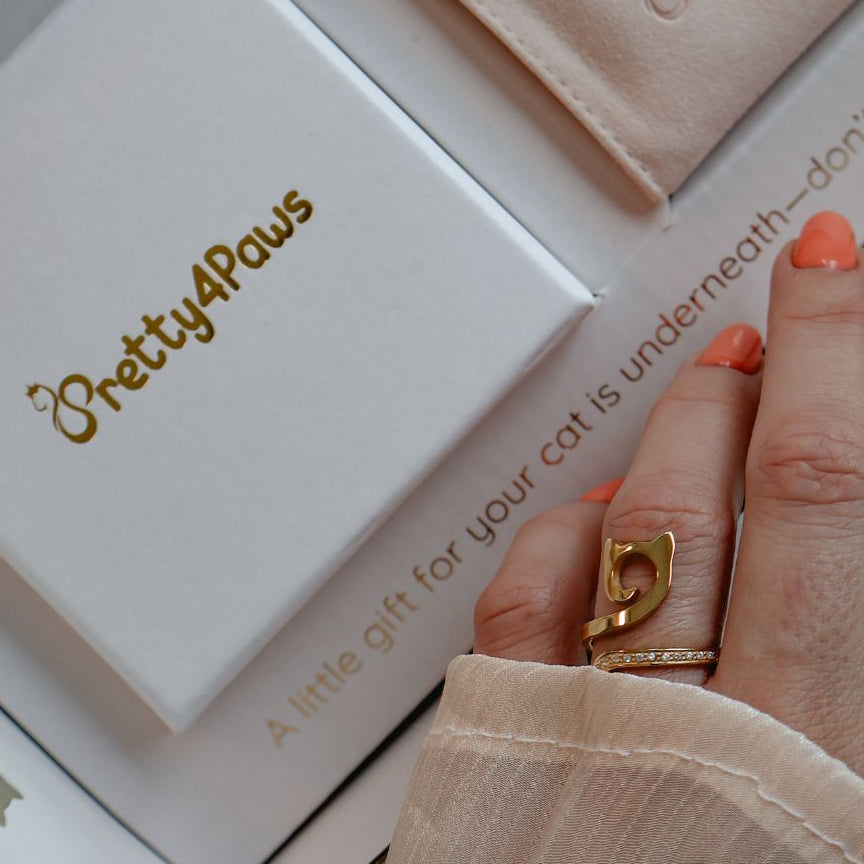 A close up lifestyle image of model's hand wearing an elegant gold cat ring with zirconia. 