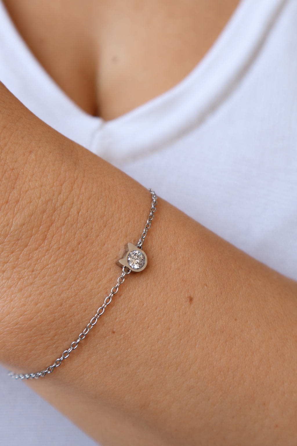 Kitty’s Sparkle cat bracelet worn on a wrist against a white top, showing the silver-tone cat-head setting and sparkling centre.
