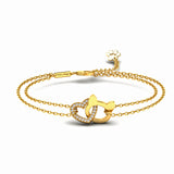 A gold double-strand chain bracelet featuring a central interlocking heart and cat head design, having heart outlined with small clear crystals, with an adjustable lobster clasp and a small paw shaped charm, shown on a white background.