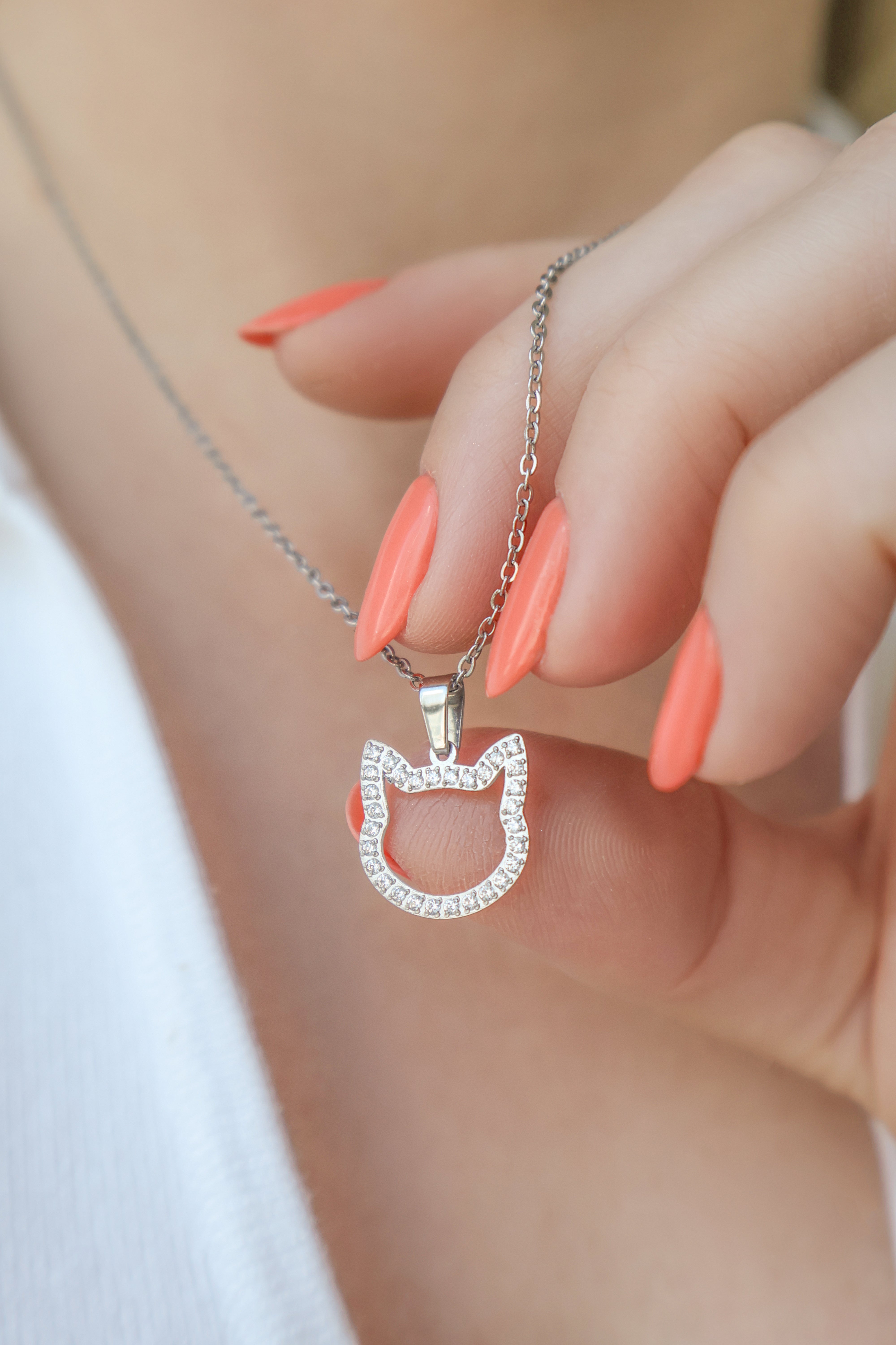 A close up image of stainless steel necklace and a cat-shaped pendant with zirconia. 
