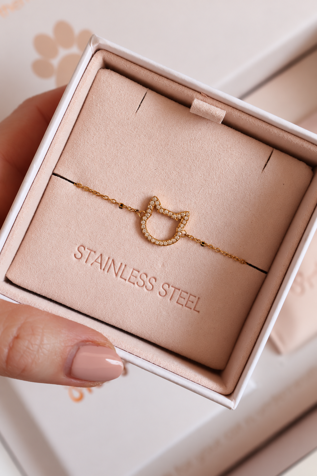 Magical Meow cat bracelet displayed in an ivory jewellery box with a blush insert, held by a hand with nude nails.