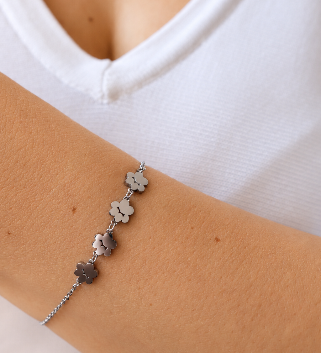 Silver Paw Prints Bracelet worn on a wrist against a white top, showing four paw-shaped charms with cut-out details.