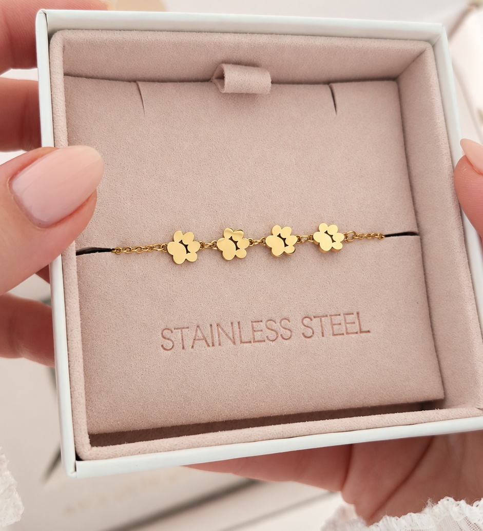 Gold-plated bracelet in a soft pink jewellery box. Bracelet has 4 pendants  in a shape of cat paw. 